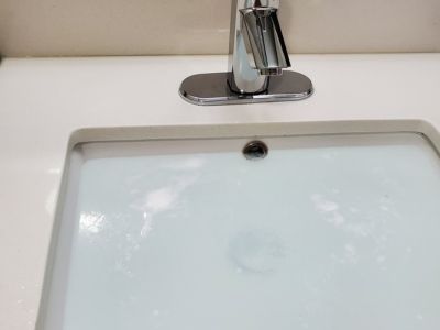 Sink with running water and bubbles, indicating potential plumbing issues related to slow drainage, relevant to hydro jetting services offered by Plumb Right.