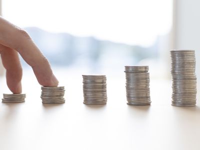Hand reaching for stacks of coins representing savings and cost efficiency related to tankless water heater installation.